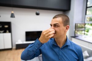 man pinching his nose because of a foul odor