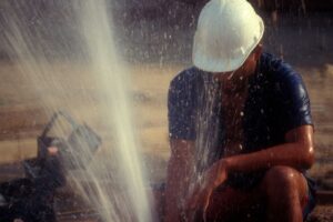 plumber getting sprayed by water while making repairs